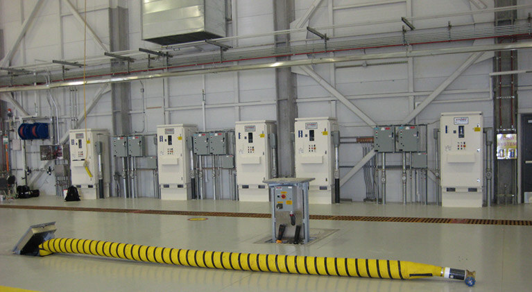 Inside an airport with a yellow industrial power cord on the ground surrounded by equipment.