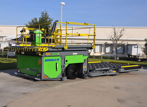  The image shows a large green and yellow Ranger 15E vehicle near a truck loading dock.